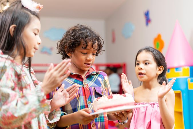 Boy blowing out birthday candles on cake at school