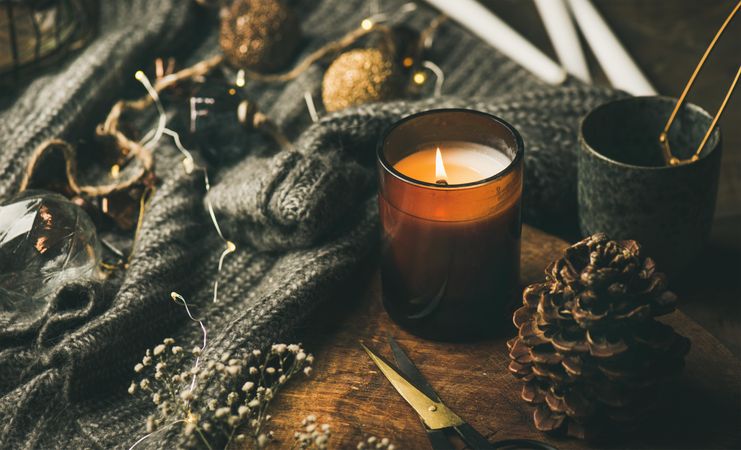 Candle, tea, and festive decorations arranged around a woolen sweater