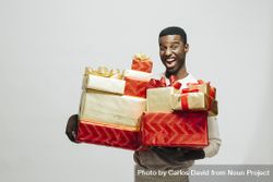 Excited Black man holding pile of wrapped presents in both arms bxgBa4