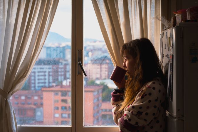 Woman enjoying hot beverage near fridge