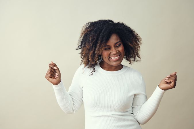 Portrait of happy Black woman with both hands up dancing