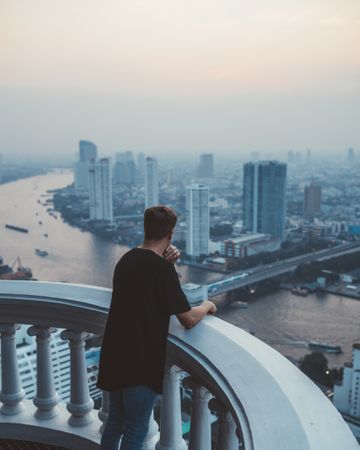Man on balcony viewing Bangkok in haze