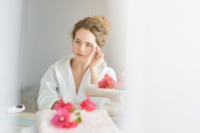 Woman wiping face with cotton pad