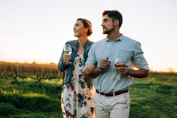 Couple walking together with a glass of wine in vineyard
