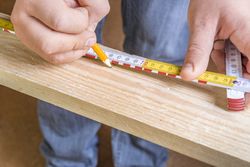 Carpenters hands with pencil and measuring tape