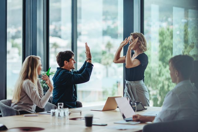 Female CEO giving double high five to colleague