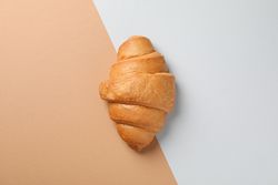 Freshly baked croissant on nude two tone background, top view
