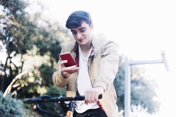 Man on a bicycle looking down at mobile phone