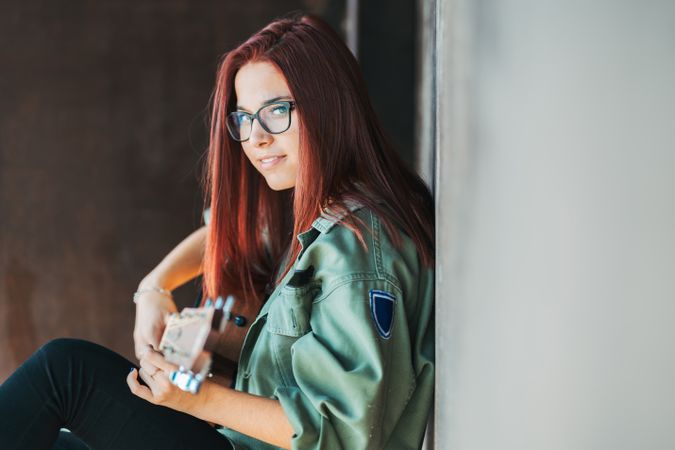 Romantic woman playing guitar leaning on wall