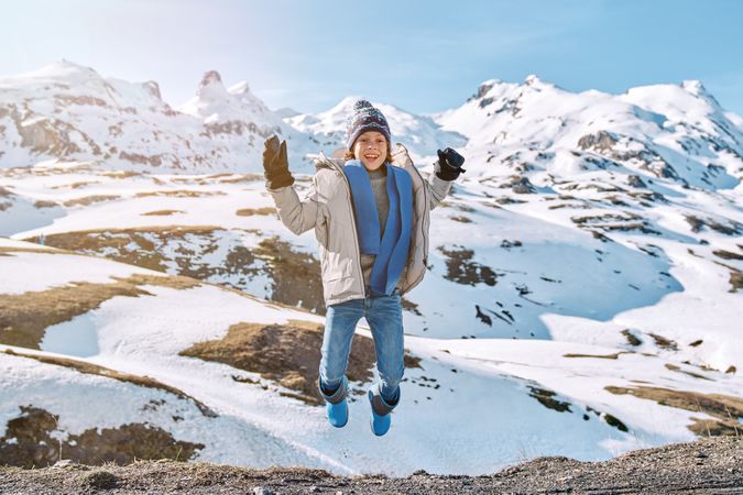 Cheerful boy jumping in snowy mountains