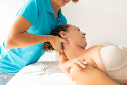 A female physiotherapist performs a stretching exercise on her patient's neck and shoulder