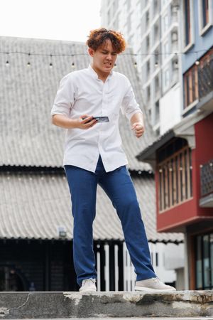 Asian man holding mobile phone standing outside