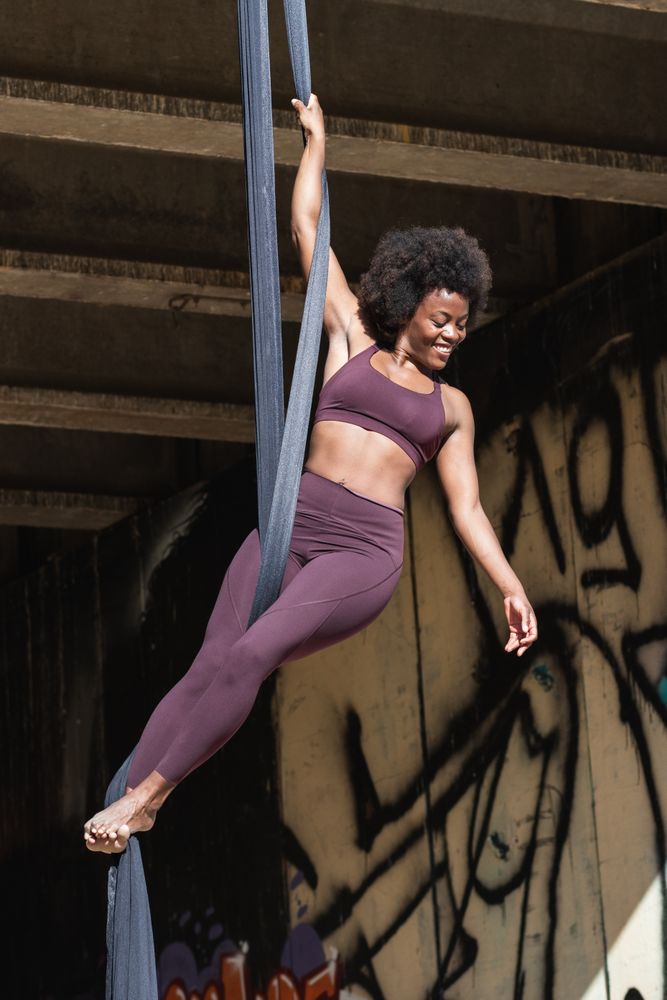Fit woman doing yoga with aerial silks in city