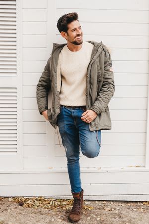 Cheerful stylish male standing against wooden wall