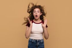 Young girl with hair blowing upwards, expressing surprise
