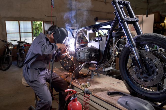 Faceless mechanic working with welding machine while repairing m