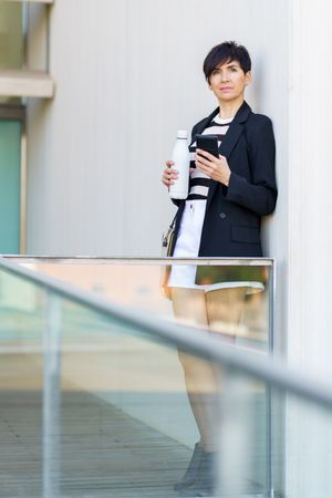 Woman leaning outside building with bottle