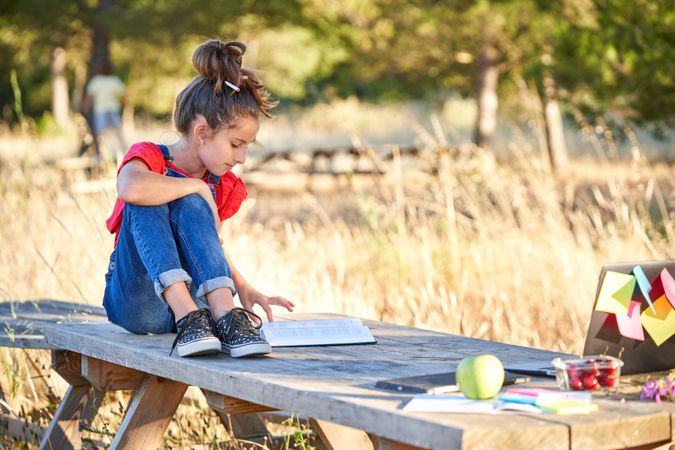Cute girl sitting on wooden table with book