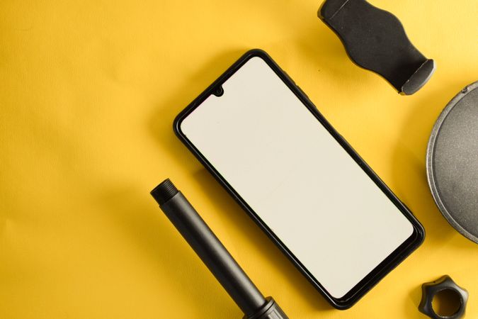 Mock up phone and circular accessory on yellow table with copy space