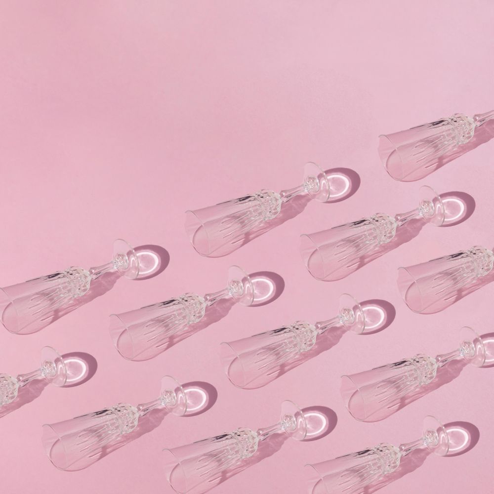 Pattern of champagne flutes on pink background, copy space