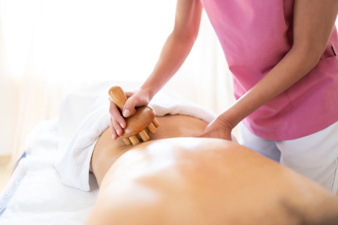 Masseuse massaging lower back of woman in spa