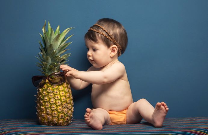 Happy baby playing with a pineapple