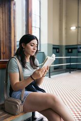 Woman reading a book sitting on a bench