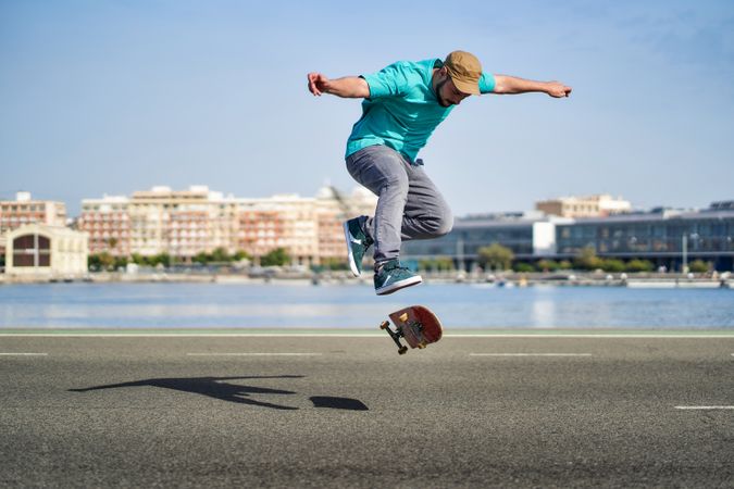 a man doing an ollie 360 flip with his skateboard down a road
