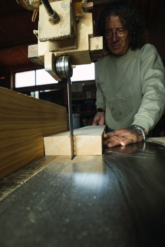 Mature male woodworker cutting plank with band saw