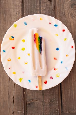 Ice cream on wooden stick with LGBTQIA symbol on decorated plate