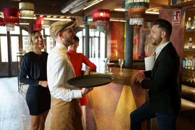 Bartender laughing with guests in bar