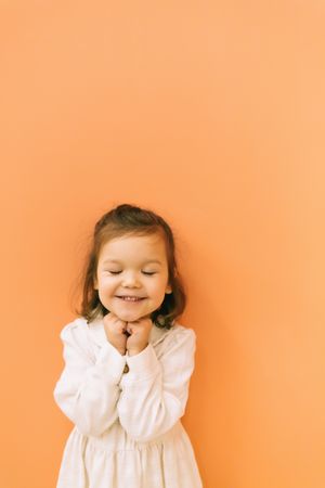 Smiling little girl near orange wall