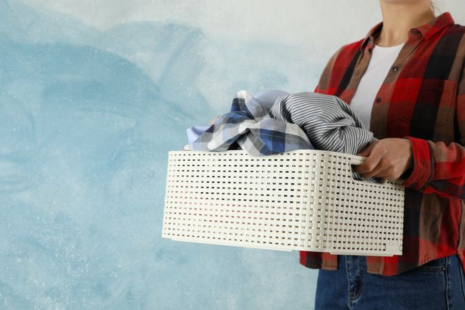 Young woman hold basket with clean clothes, space for text