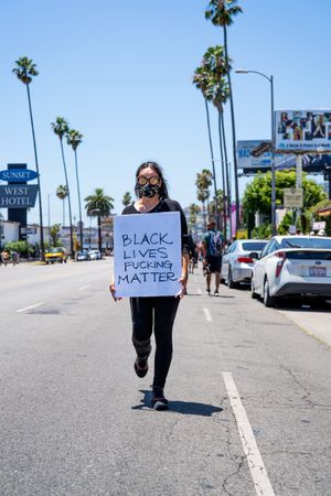 Los Angeles, CA, USA — June 14th, 2020: Woman standing in city street with protest sign at BLM march