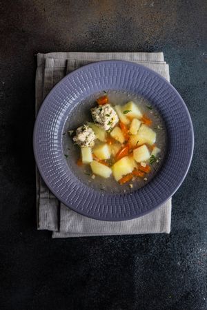 Healthy soup with potato and carrot and meat balls served on the table, vertical