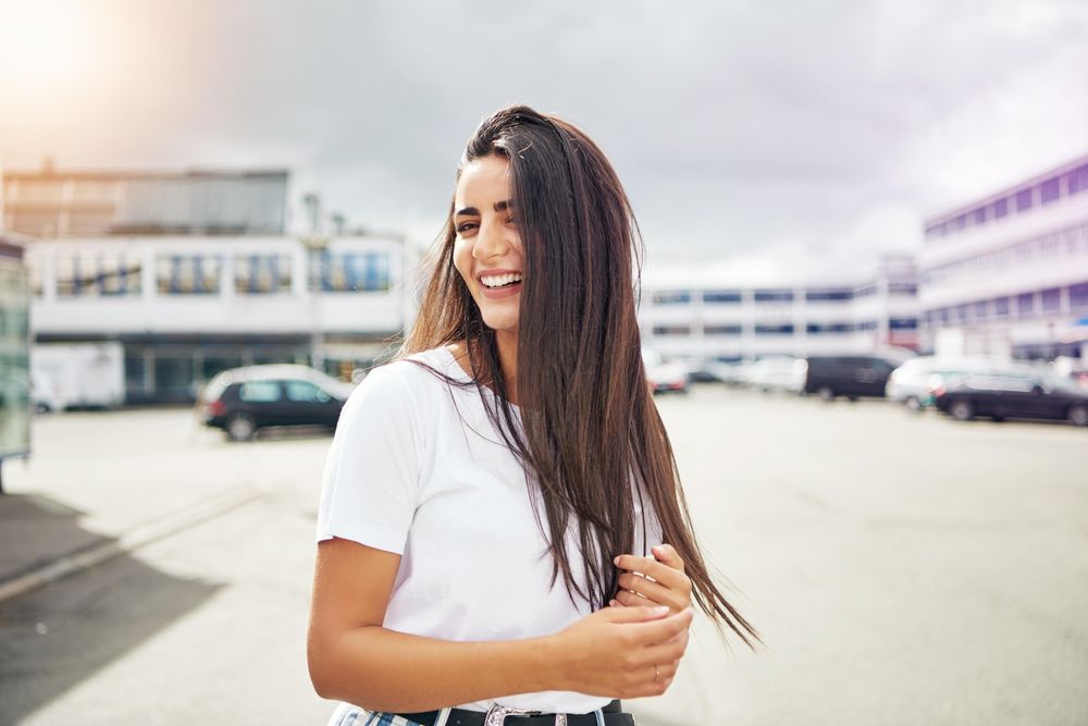 Smiling coy woman playing with her hands on a street