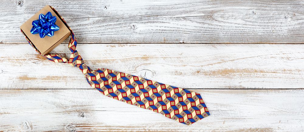 Gift box with knotted dress tie on rustic wood with plenty of copy space