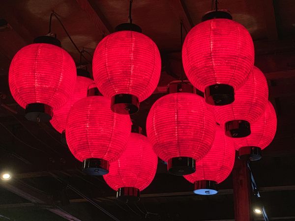 Red lit Lanterns hanging from the ceiling at night in Japan