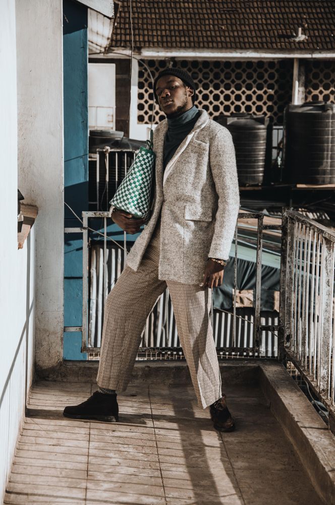 Man wearing gray suit holding a purse standing beside balcony fence