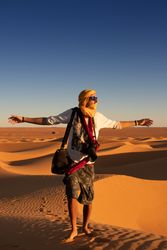 Anonymous traveler in desert during sunset