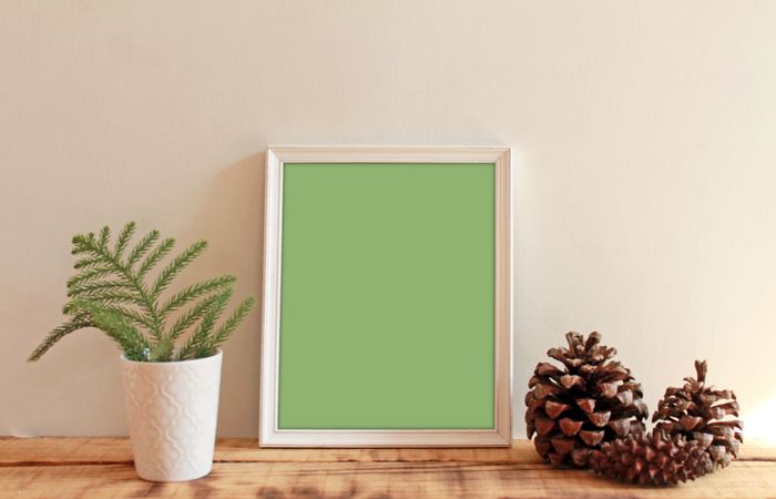 Rectangular picture frame with green interior mockup with pinecones and branch in vase
