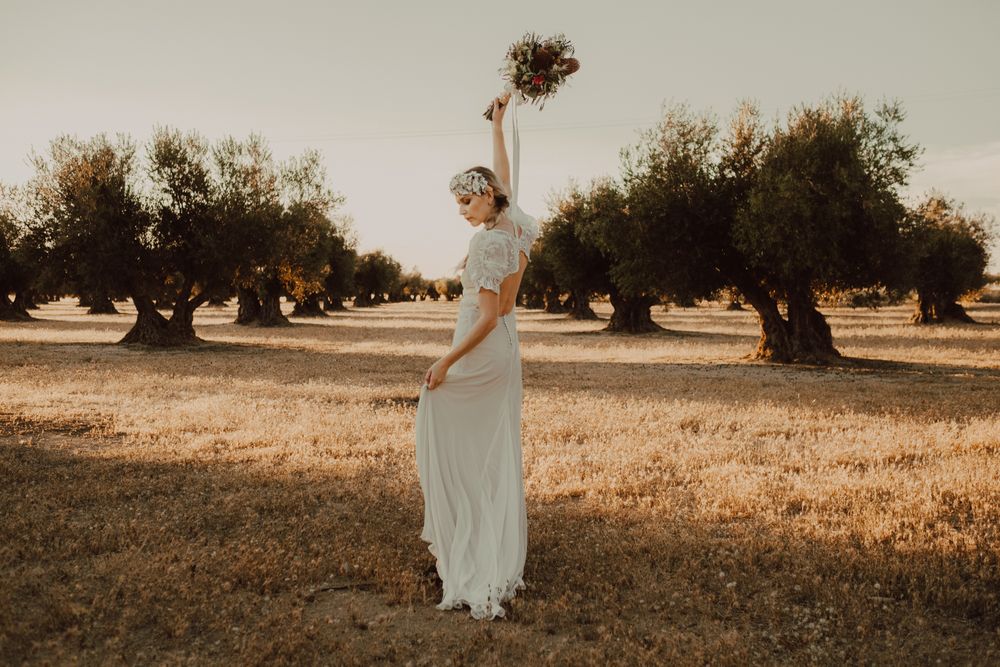 Content woman in dress with open back raising hands with flower bouquet