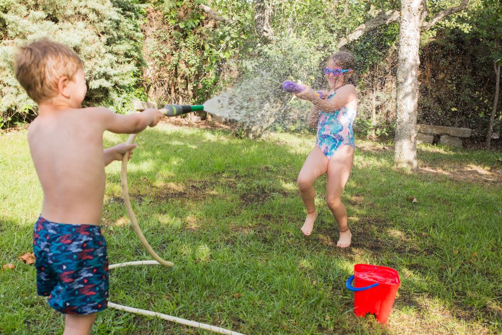 Little kids in swimwear having fun with splashing water