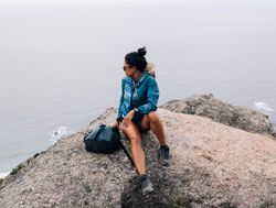 Female sitting on rock looking over view of ocean on overcast day