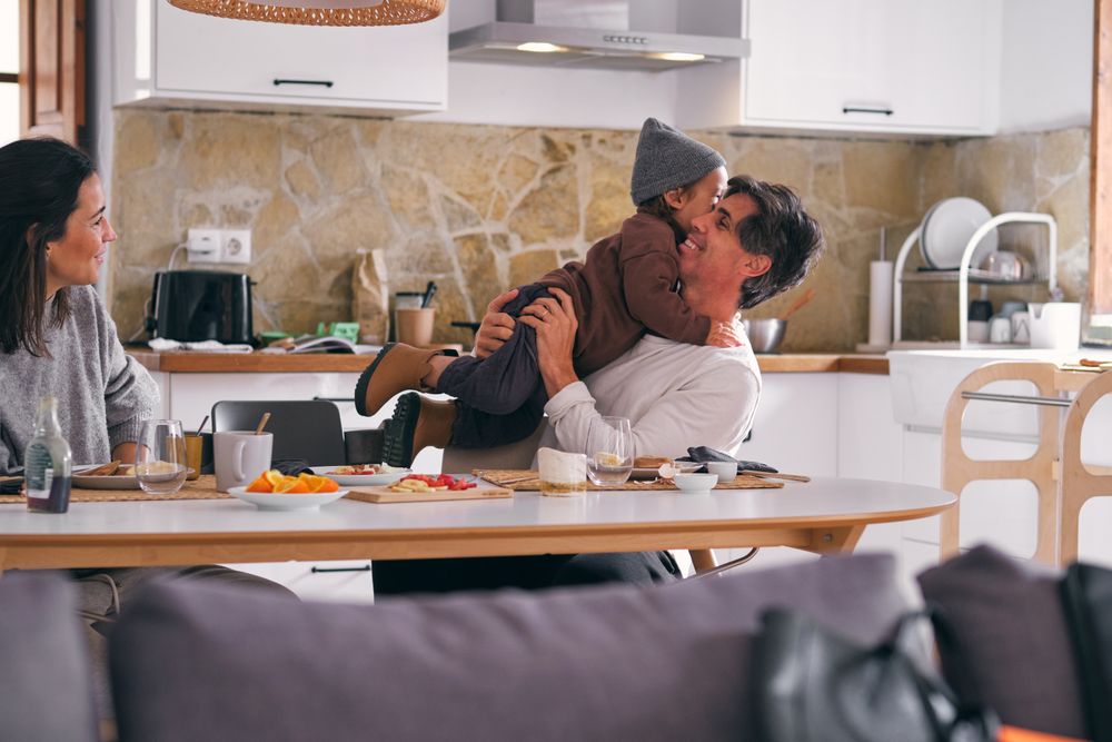 Happy father embracing anonymous daughter against wife in kitche