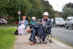 Older people sitting on sidewalk during drawing class
