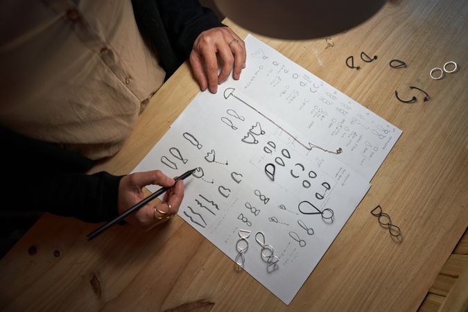 Crop jeweler drawing sketches on table