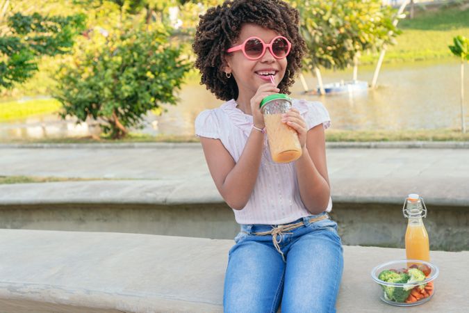 Girl drinking smoothie at the park. Healthy eating