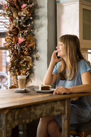 Cheerful woman talking on phone in cafe
