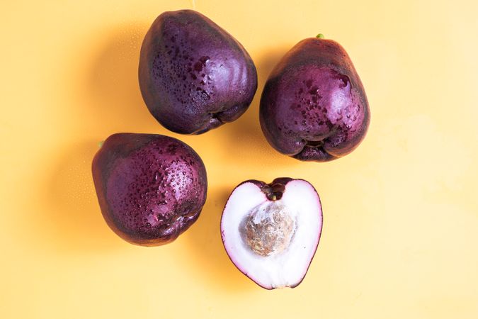 Four Syzygium malaccense or known as jambu jamaika fruits are on a yellow background